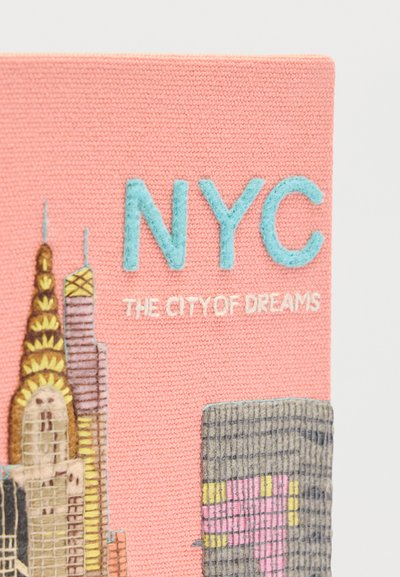 Ροζ ύφασμα με ραμμένα γράμματα NYC και τη φράση «Η Πόλη των Ονείρων», με κεντημένους ουρανοξύστες της Νέας Υόρκης σε κίτρινο, γκρι και ροζ.