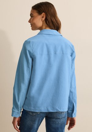 Chemise en velours côtelé bleu clair à manches longues et col. Équipée de poignets à boutons et d'un ourlet droit, mettant en avant une finition texturée.