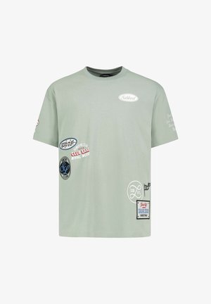 Light green short-sleeve T-shirt with multiple small printed logos and patches including "Sublevel," "Good Stuff," and "Club Lane."