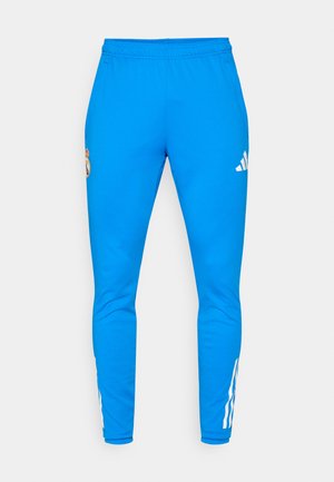 Modre športne hlače z elastičnim pasom, z belim adidasovim logotipom in grbom Real Madrida. Gladka tekstura in slim fit zasnova.