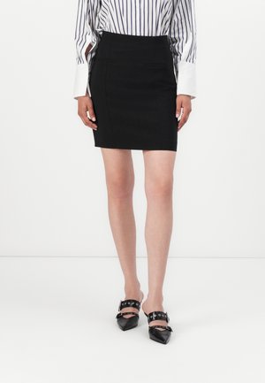 Black fitted mini skirt with two front pockets, made of smooth material. Paired with black pointed-toe shoes featuring strap accents.