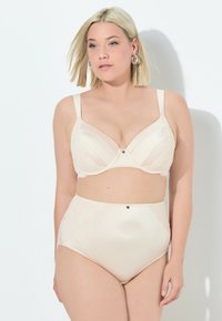 Completo lingerie beige con reggiseno a coste testurizzate e dettagli in pizzo, accompagnato da un pantaloncino a vita alta, entrambi adornati con piccoli bottoni decorativi.