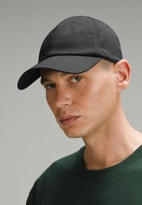 Černá látková kšiltovka s zakřiveným vizérem, na boku s jemným logem. Kšiltovka má hladkou texturu a přiléhavý design.