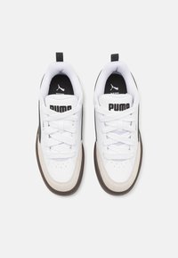 Bílé sportovní boty s černými detaily, strukturovanou krémovou špičkou a logem na jazyku a boku. Šněrovány plochými bílými tkaničkami.