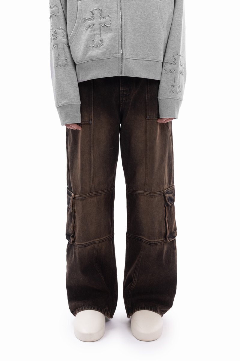 Szürke cipzáras kapucnis pulóver kereszthímzéssel és barna, több zsebes, bő szabású cargo nadrág. Vastag, fehér platform cipő.