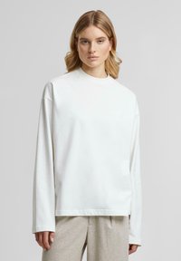 Weißer langärmeliger Sweatshirt mit hohem Kragen, aus weichem Baumwollmaterial, mit überschnittenen Schultern und lockerem Schnitt.