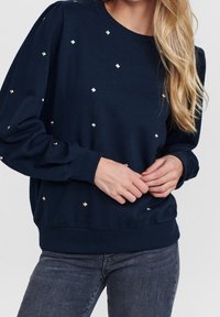 Mörkblå sweatshirt med prydnader av små, reflektiva, diamantformade detaljer. Har ribbade muddar och nederkant, avslappnad passform.