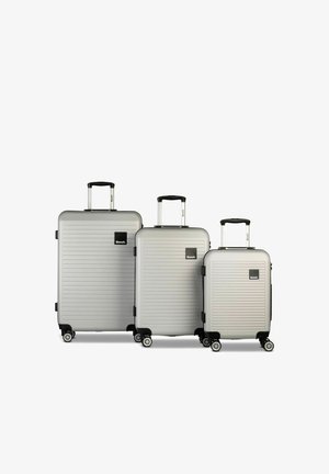 Three silver hard-shell suitcases with four wheels and telescopic handles, arranged from large to small, branded with a black Bench logo.