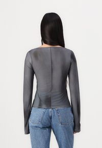 Gray long-sleeve top with a smooth, slightly sheer texture. Features a square neckline and back seam detail, paired with high-waisted blue jeans.