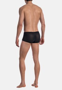 Schwarze Boxershorts aus weichem, strukturiertem Stoff mit enger Passform und elastischem Bund, von hinten auf einem nackten Oberkörper gezeigt.