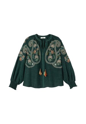 Blouse verte foncée à manches longues avec broderies florales et paisley, liens à pompons au niveau du col et poignets smockés.