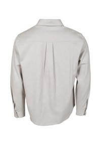 Chemise beige clair à manches longues avec empiècement au dos et pli creux central, poignets boutonnés et col classique, vue de dos.