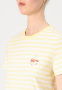 Gul og hvitstripet t-skjorte, kort erm, rund hals. Har brodert "Sommer" tekst og palme-design på brystet.