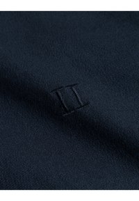 Textil marin cu o țesătură fină, texturată și un logo brodat "II" într-un fir mai deschis, plasat subtil în interiorul materialului.