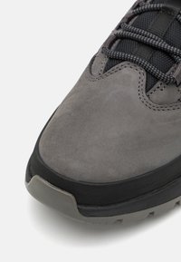 Baskets en daim gris avec dessus en mesh noir texturé, bout arrondi et semelle en caoutchouc noir. Présentent des accents gris et des lacets texturés.