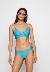 Conjunto de bikini turquesa com um top triangular e cueca de cintura alta a condizer, apresentando textura estriada e alças finas ajustáveis.