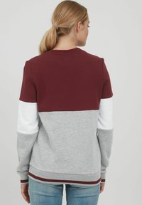 Burgunder- og grå hettegenser med hvite ermer, med et fargeblokkdesign, ribbestrikket nederkant og myk tekstur. Rund hals.