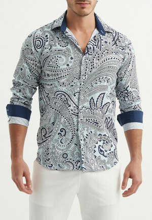 Chemise bleu clair à manches longues avec un motif paisley bleu marine. Col et poignets bleu marine contrastants, avec un tissu texturé et un design à boutons sur le devant.