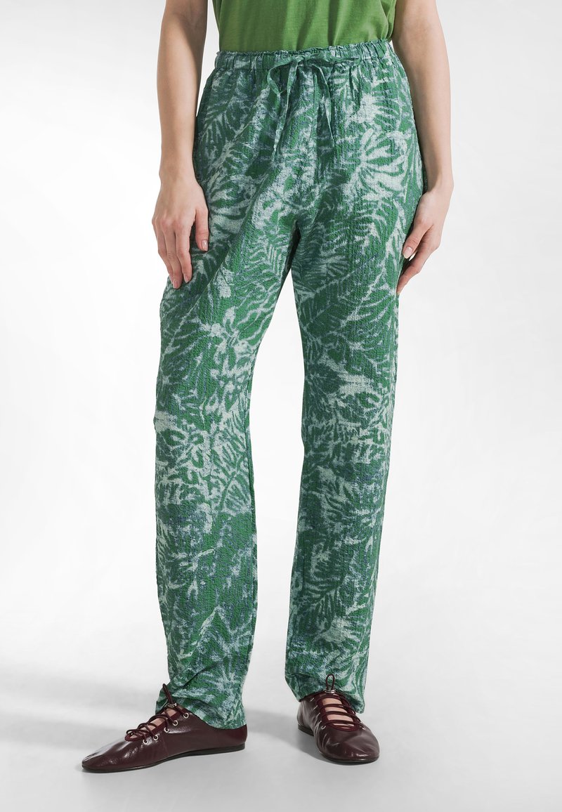 Zielone spodnie w kwiaty o luźnym kroju z elastycznym paskiem w talii, wykonane z fakturowanej tkaniny, wykończone regulowanymi mankietami.
