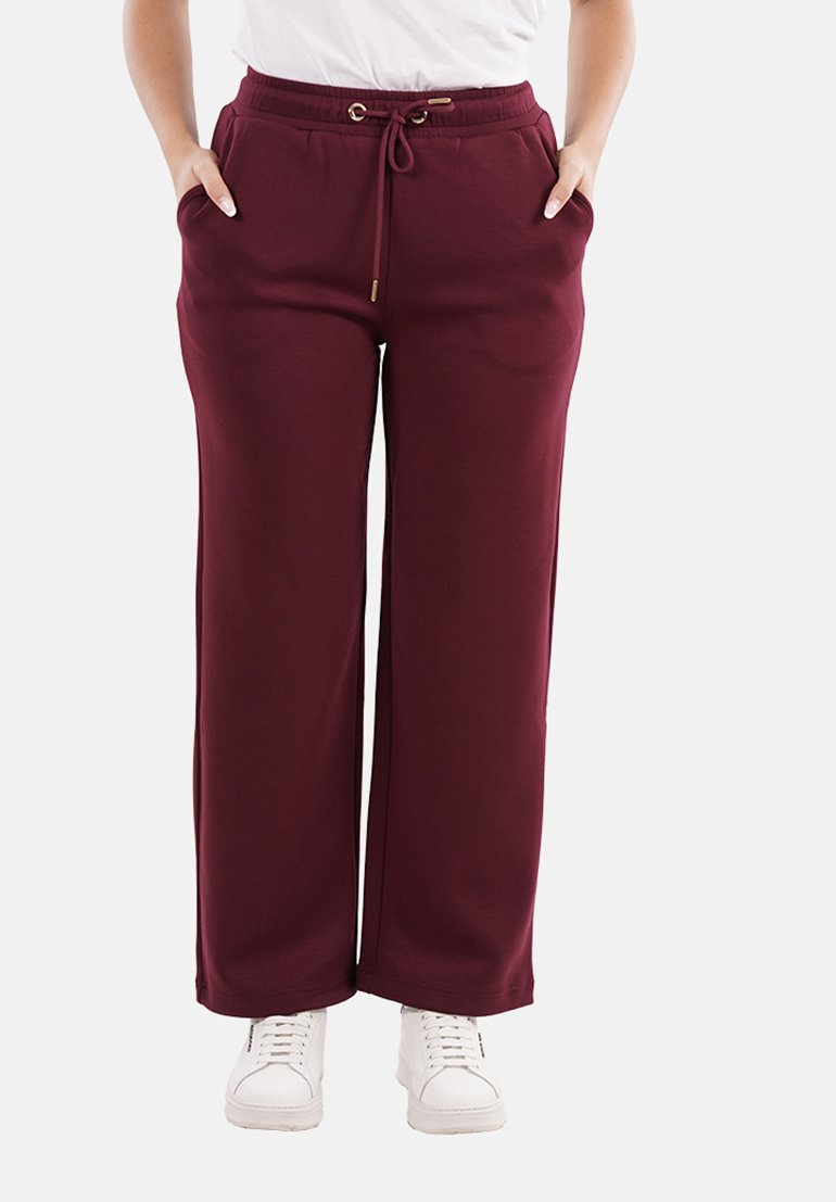 Pantaloni della tuta bordeaux realizzati in materiale morbido, con vita elastica, chiusura con lacci e tasche laterali, caratterizzati da una vestibilità comoda.