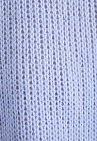 Ljusblått stickat tyg med ett öppet stickmönster, som visar en mjuk textur och fina garn detaljer i en närbild.