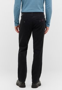 Czarne spodnie z korduroyu o prostym kroju, z dwiema tylnymi kieszeniami i małym detalem z logo w pobliżu prawej kieszeni.