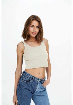 Beige ribbed crop top with wide shoulder straps, paired with high-waisted denim jeans featuring a light and dark blue color block design.