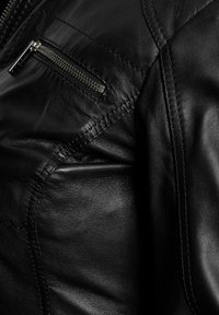 Crna kožna jakna s patentnim zatvaračem, glatke teksture, suptilnim šavovima i prilagođenim dizajnom s krojenim linijama.