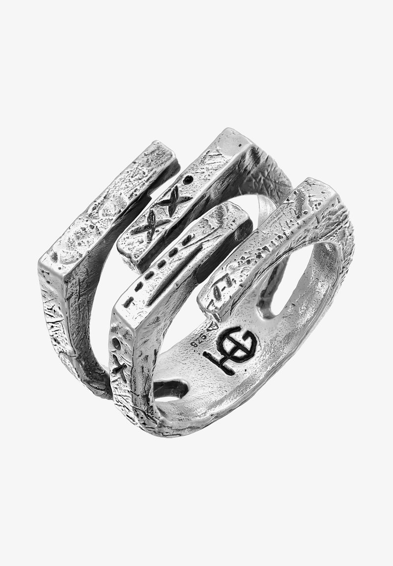 Bague en argent présentant un design abstrait avec des surfaces texturées et inégales, et des barres rectangulaires qui se chevauchent. Marquée d'un logo à l'intérieur.