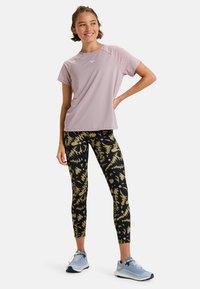 Light purple athletic shirt with short sleeves, paired with black leggings featuring yellow and pink abstract patterns. Light blue running shoes.