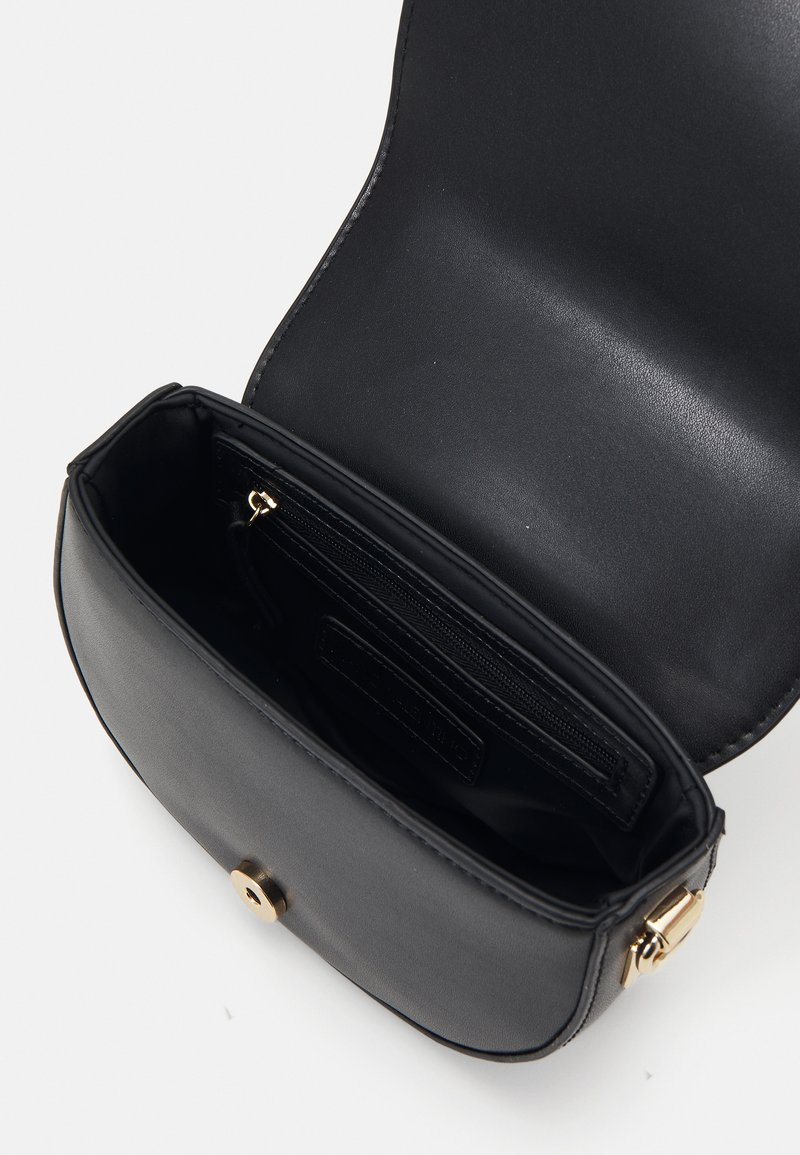 Borsa a tracolla in pelle nera con forma arrotondata, hardware color oro e una tasca interna con zip. Texture liscia e design interno minimale.