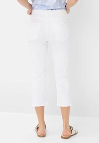 Jean blanc court avec une taille ajustée, deux poches arrière et une texture en denim standard. Les jambes se rétrécissent jusqu'à un ourlet juste au-dessus de la cheville.