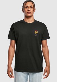 Sort bomulds T-shirt med et hexagonalt broderet logo med en høne, en fodbold og tre stjerner på venstre brystområde.