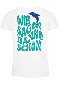 Bílý tričko s barevným, zaobleným textem zelené barvy "WIR SAGEN DANKE SCHÖN" a modrou grafikou delfína nad textem.