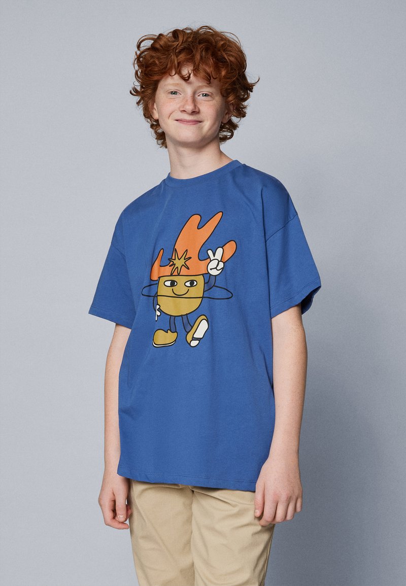 Sinise puuvillane T-särk, millel on koomiksitegelase print oranžide detailidega. Lõdva lõikega, lühikeste varrukatega ja ümar kaelus.