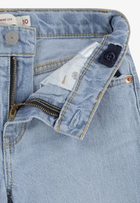 Světlé modré džíny s širokými nohavicemi, zlatý zip, tmavě modrý knoflík a kontrastní šití. Mají pevný pas a vnitřní kapsu.