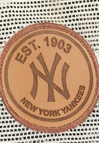Brauner Lederpatch mit einem erhabenen "NY"-Logo, dem Text "EST. 1903" und "NEW YORK YANKEES", umrandet von einem dunkelbraunem gesteppten Rand.
