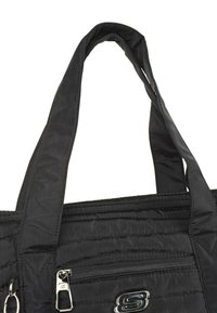 Bolsa tote negra acolchada con asas de tela dobles, bolsillo frontal con cremallera y un acento del logo plateado. El material parece suave y liviano.