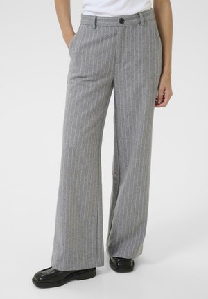 Gray pinstripe trousers with a high waist and wide legs, paired with a white top. The model's hand rests casually in a pocket.