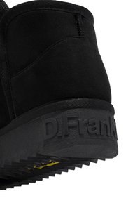 Botín negro de ante a la altura del tobillo con suela de goma texturizada, detalle de logo en relieve y un diseño elegante con un collar acolchado.