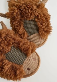 Brune pelsvipper med teksturerede mønstre, et plaid-akkent og afrundede former med syede ansigtstræk og ører.