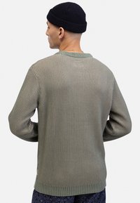 Grüner, gerippter Strickpullover mit langen Ärmeln, Rundhalsausschnitt und strukturiertem Design. Mit einem dezenten Streifenmuster und einem gesäumten Saum.