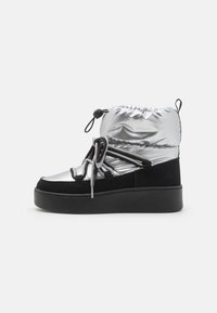 Silver and black ankle boot with a shiny, padded upper, featuring a cinched top, black suede accents, and a thick black platform sole.