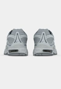 Par de zapatillas deportivas de malla gris vistas desde atrás, mostrando suelas acolchadas y el logo de Nike en cada talón.