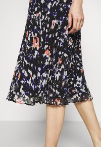 Černé plisované šaty s vícero barevným abstraktním potiskem v růžové, bílé a modré barvě. Lehká látka s plynulým designem.