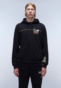 Felpa nera con cappuccio in tessuto morbido, presenta un design grafico arancione, tasca frontale e polsini a costine. Abbinata a pantaloni jogger neri coordinati.