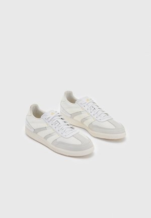 Pair of white and light gray low-top sneakers with lace-up fronts and subtle logo detailing on sides and tongue, on plain background.