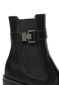 Stivale ankle in pelle nera con pannello elastico laterale, fibbia metallica decorativa e suola spessa in gomma.