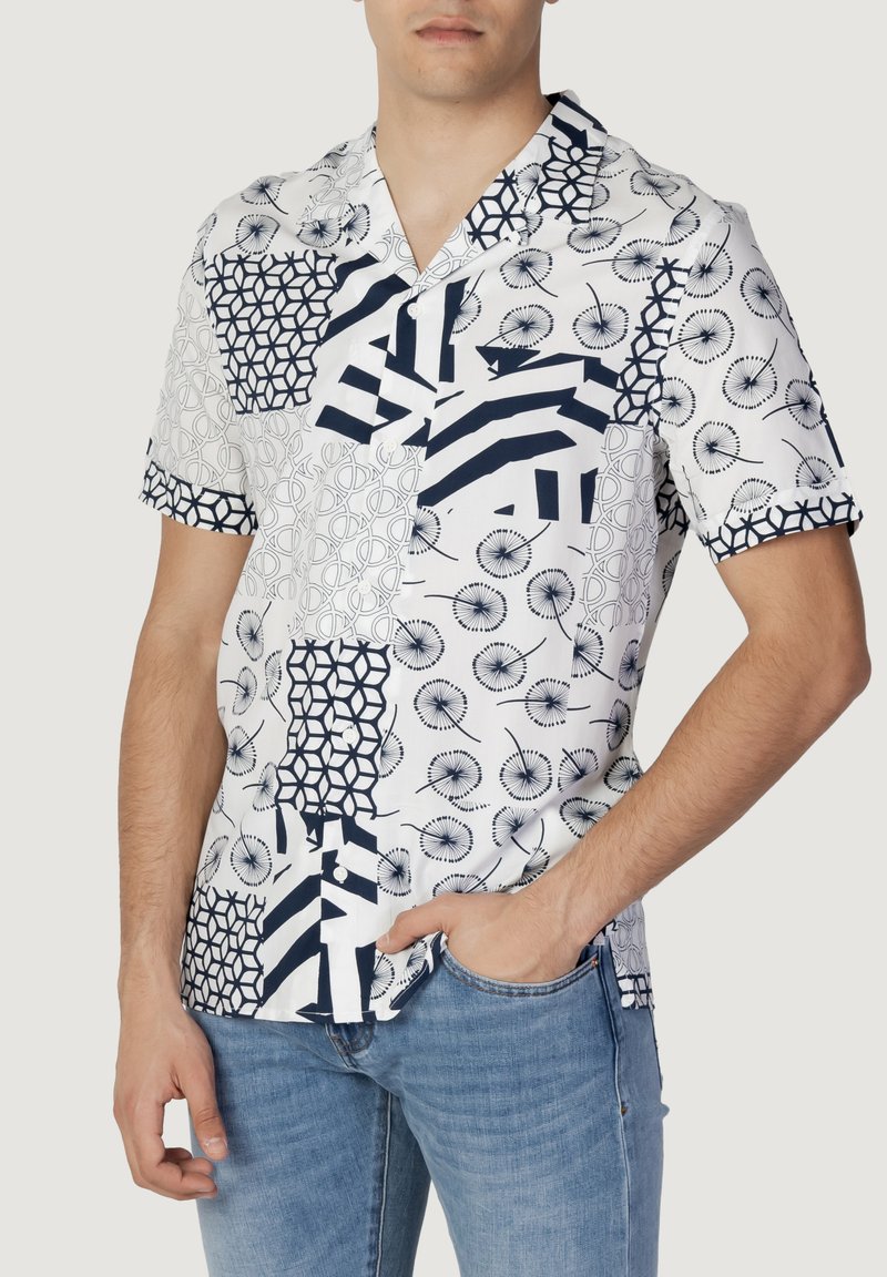 Korte mouwen button-up shirt in het wit met blauwe geometrische patronen, met verschillende texturen en ontwerpen op verschillende secties.