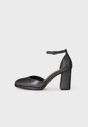 Black textured heel shoe with a rounded toe, ankle strap, and a block heel. The material has a slight shine and a smooth finish.